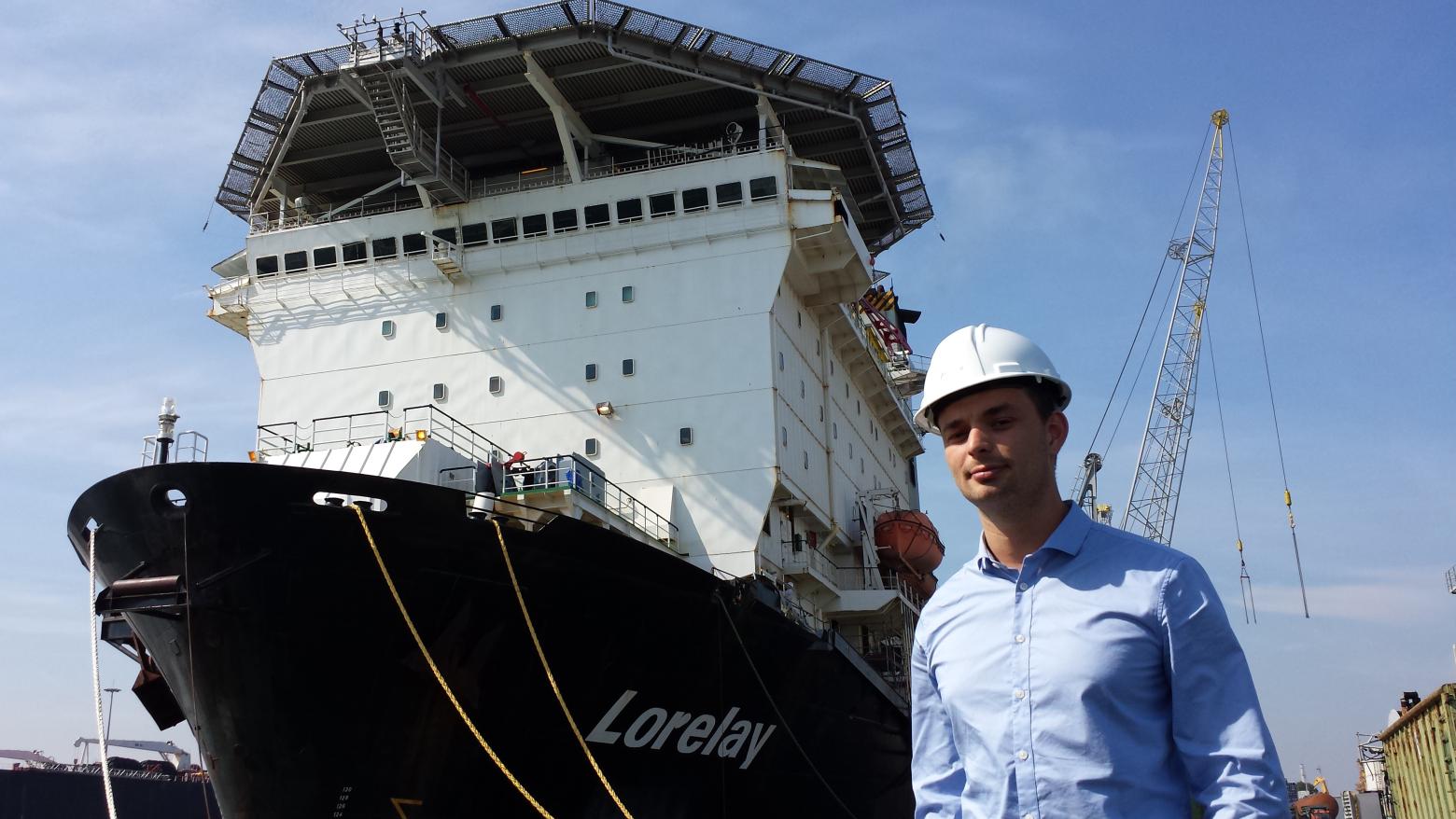 Justin stands confidently in front of a large ship.