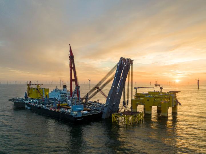 Offshore wind farm construction in the North Sea, featuring Pioneering Spirit installing TenneT's 900-MW converter station.